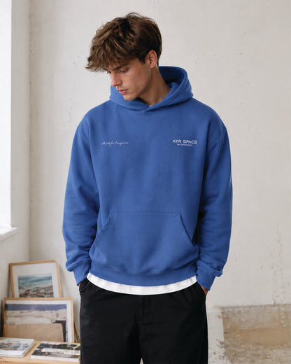 Person wearing a blue hoodie with front graphic print detailing.