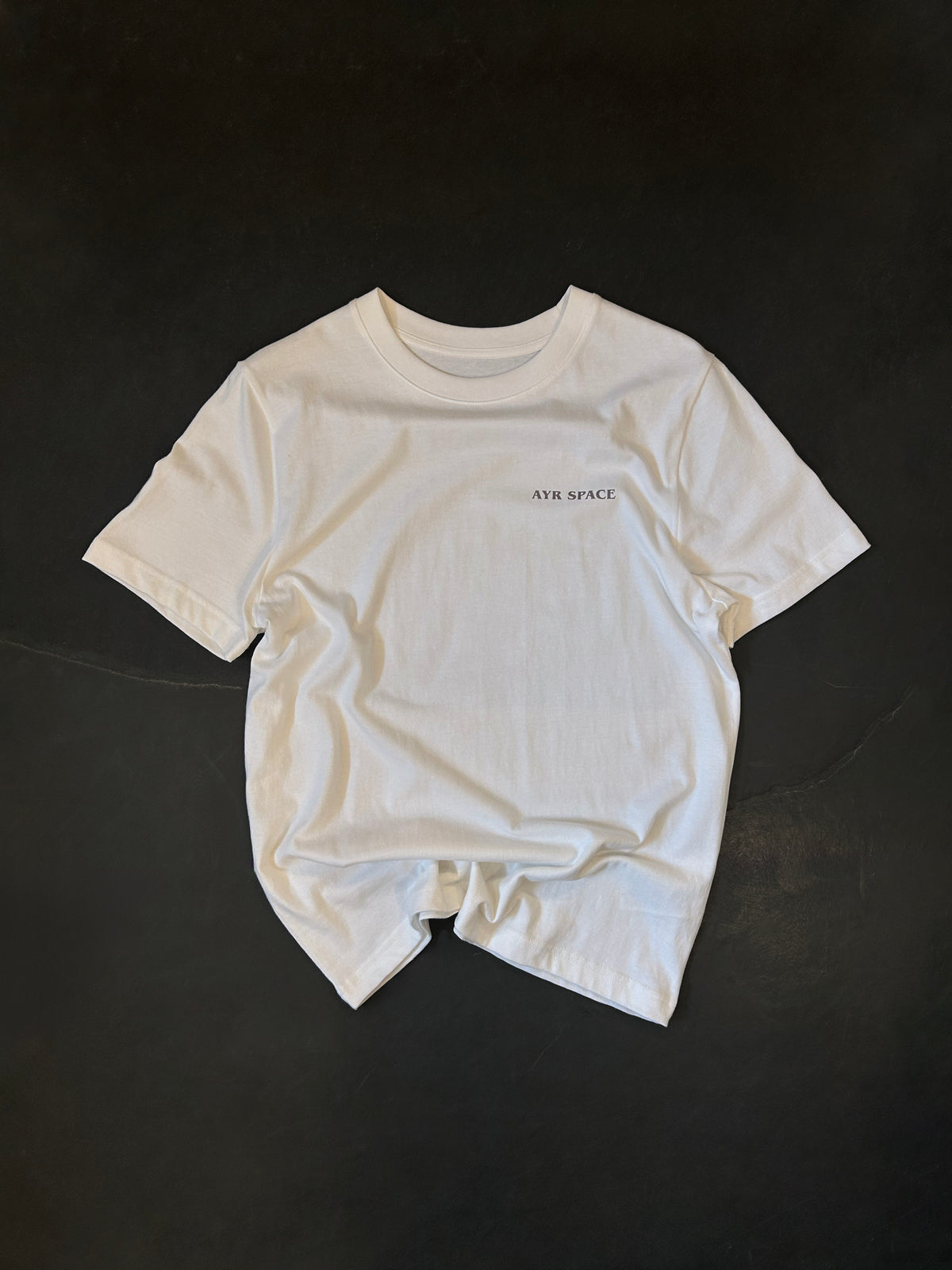 Front of the AYR SPACE Pasty T in off-white, laid flat, with a small faded brown AYR SPACE wordmark on the left chest