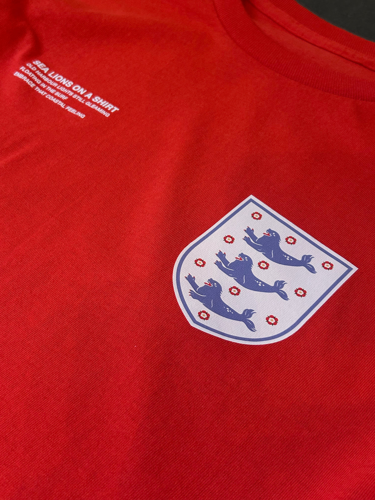 Close-up of the Sea Lions Long Sleeve in Away Red: retro-style crest with three sea lions on the chest, beside the white "Sea Lions on a Shirt" text print