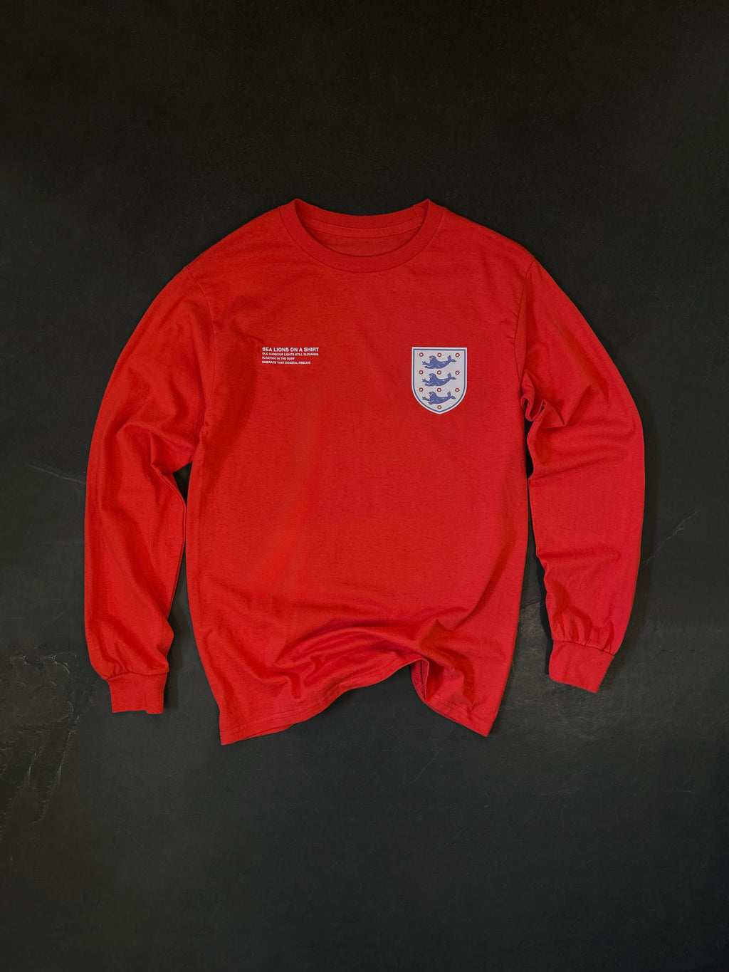 Front of the Sea Lions Long Sleeve in Away Red, laid flat: retro-style crest with three sea lions on the chest and a small white text print opposite