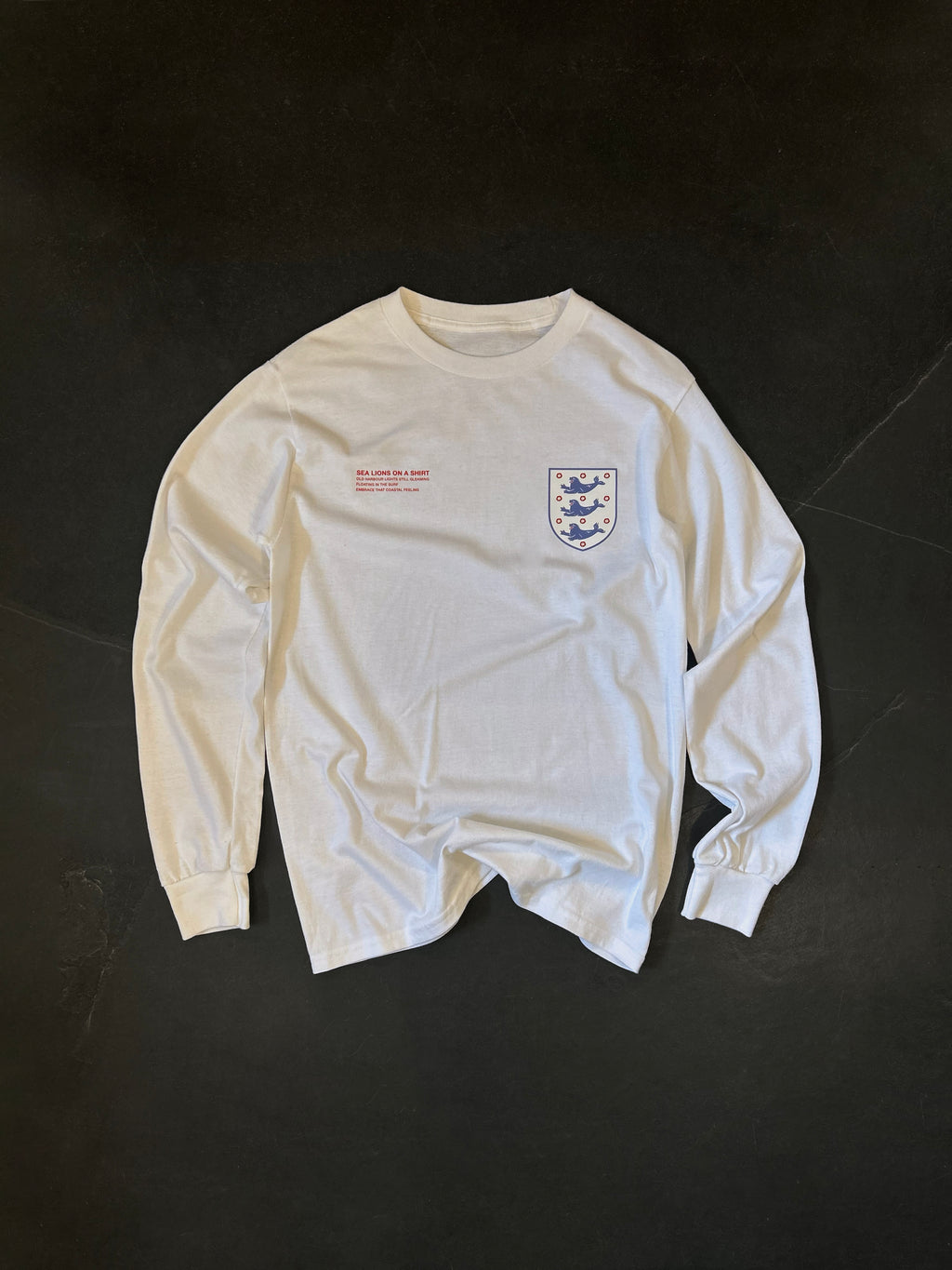 Front of the Sea Lions Long Sleeve in Home White, laid flat: retro-style crest with three sea lions on the chest and a small red text print opposite